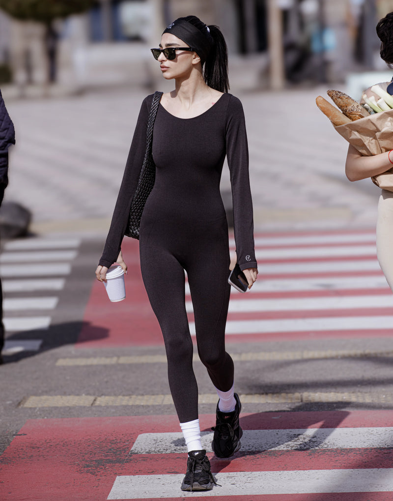 Person in a black outfit crossing a street with a crosswalk. %Black% %Hover%
