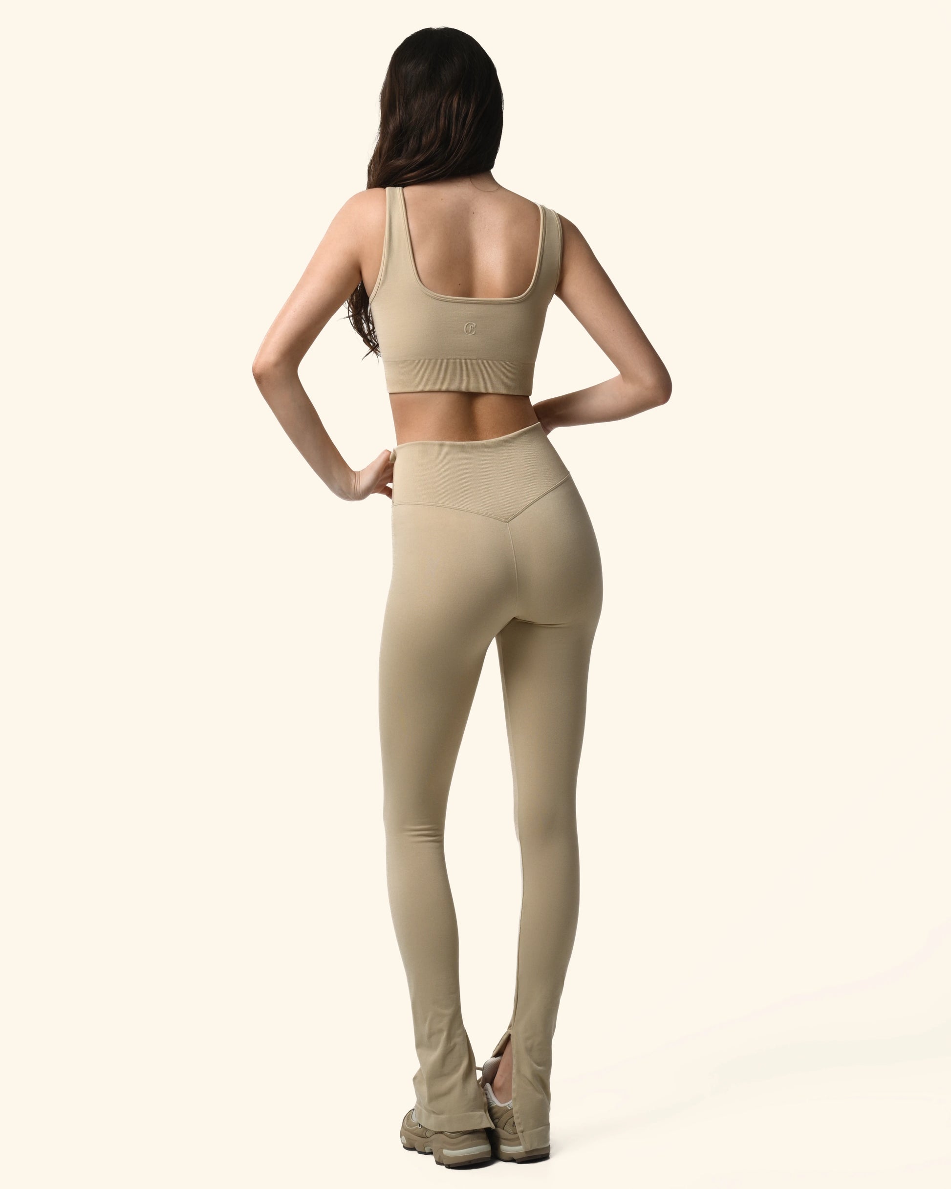 Woman wearing a beige sports bra and leggings on a white background %Cream%