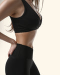 Person wearing a black sports bra and leggings on a white background %Black%