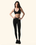 Woman wearing a black sports bra and leggings on a white background %Black%