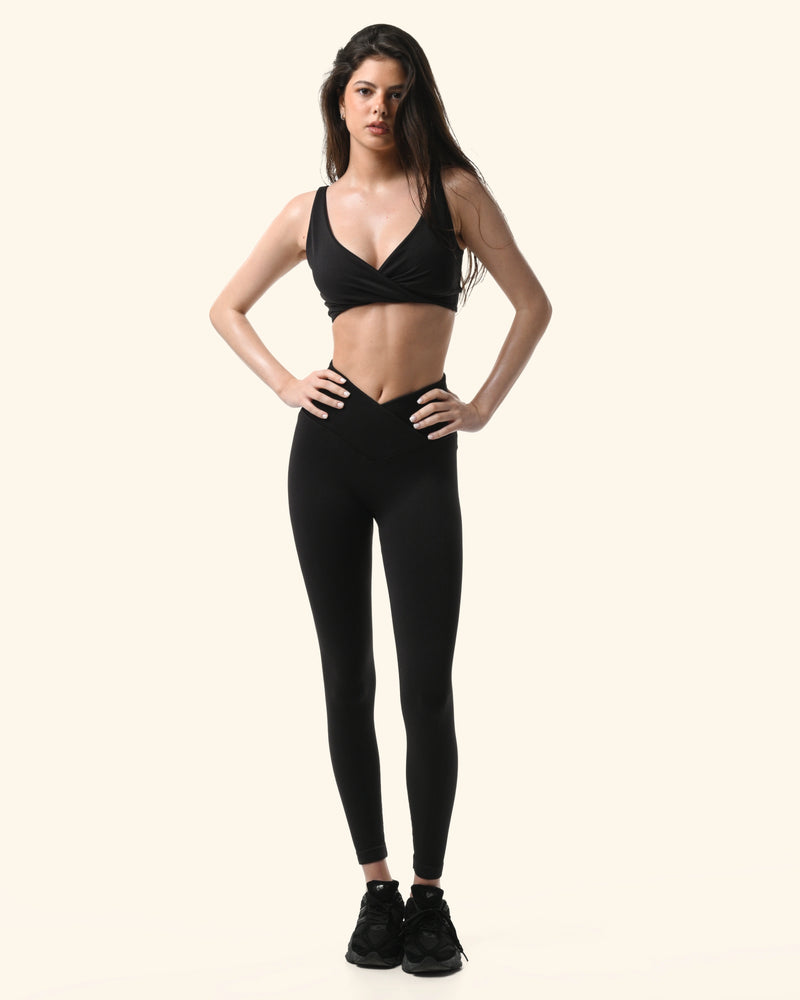Woman wearing a black sports bra and leggings on a white background %Black%